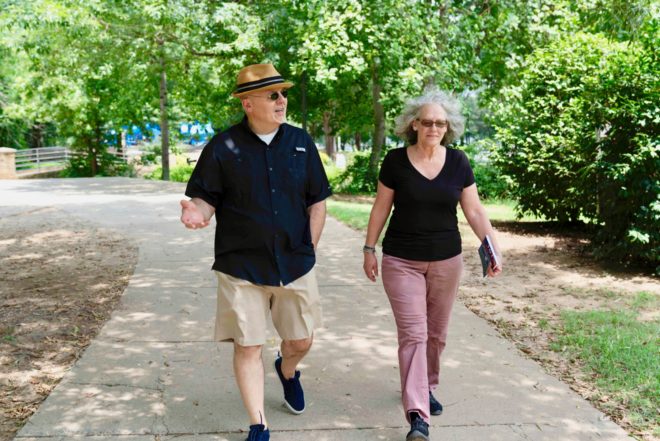 middle aged couple walking along a park path talking