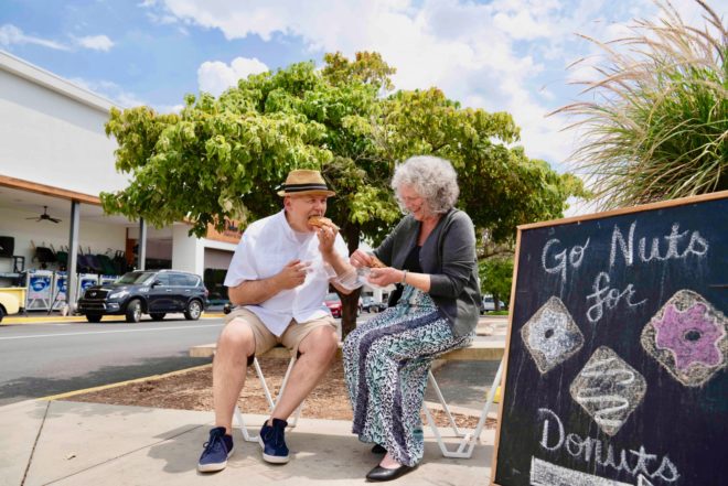 elderly couple eating donuts outside a shopping center