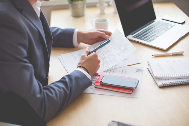 male professional working at table with laptop and papers